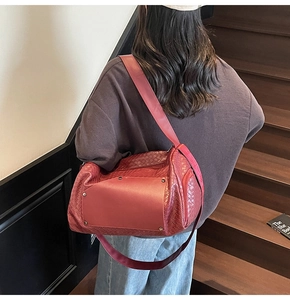 Detail view of burgundy woven tote bag with retro rivets on a model's shoulder