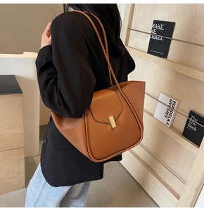 Dettaglio di una borsa tote in pelle caramello con fibbia dorata sulla tracolla sottile