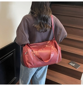 Close-up of red woven travel bag on stairs with detachable shoulder strap and handle