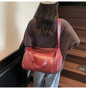 Detail view of burgundy woven leather travel tote bag showing the strap and handle