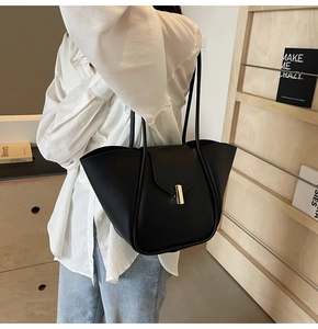 Dettaglio di una borsa tote nera grande con chiusura dorata e design ad ala vintage