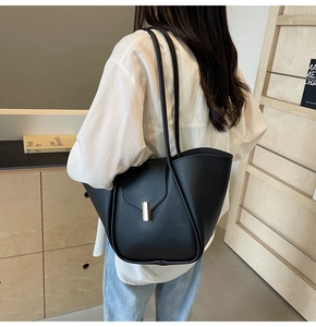 Dettaglio di borsa tote in pelle nera minimalista con elegante fibbia in metallo oro