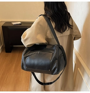 Detailed view of the black woven texture and metal rivets on this large travel tote bag