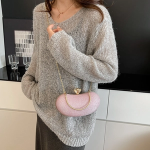 Pink glitter evening clutch bag with gold chain strap and crown clasp on a model