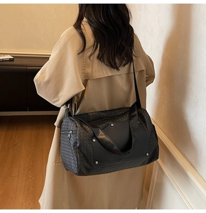 Detailed side view of black woven travel bag with studs held by model in home setting