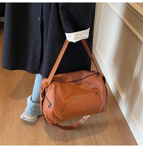 Detailed close-up of brown woven leather texture and metal zipper on the large tote bag