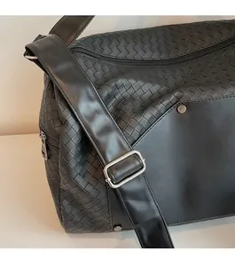 Macro detail of black intrecciato woven leather bag and silver square metallic buckle