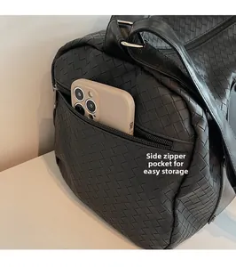 Detail of the woven black leather travel bag showing a functional side zipper pocket
