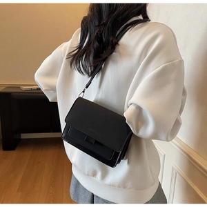 Detailed view of black leather crossbody bag featuring an embossed flap and wide strap