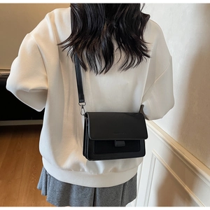 Rear view of a model wearing the black matte leather flap bag with a crossbody strap