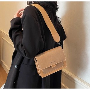 Detail of crossbody bag with wide strap and Fashion & Bags text on textured leather