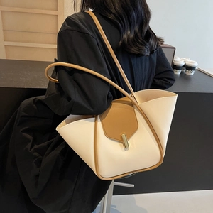 Borsa a mano moderna bicolore crema e caramello indossata da una modella al caffè