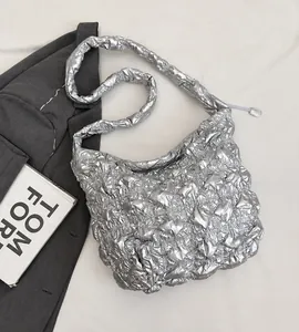Macro view of metallic silver pleated cloud bag showing quilted texture and soft padded strap