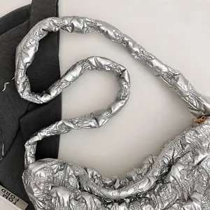Close-up of metallic silver quilted tote bag with padded strap and puffy texture