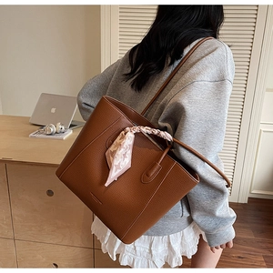 Vue détaillée du sac cabas marron grainé avec un foulard décoratif en soie sur la bandoulière