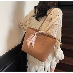 Gros plan du sac cabas marron à motif litchi avec foulard en soie sur la poignée