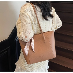 Détail d'un grand sac cabas marron à motif litchi avec foulard en soie et fines bandoulières