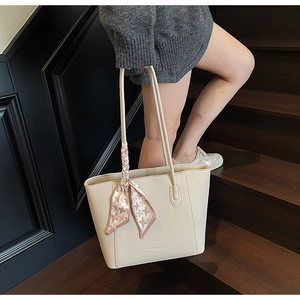 Gros plan d'un sac cabas en cuir beige avec foulard en soie élégant sur la poignée