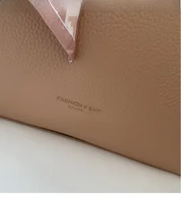 Close-up of brown litchi grain leather tote bag with elegant silk scarf decoration
