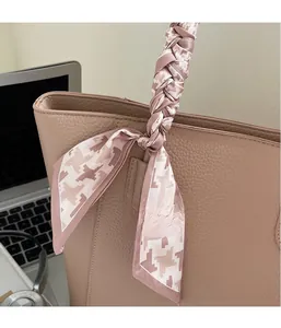 Detail of elegant houndstooth scarf wrapped on the handle of a beige leather tote bag