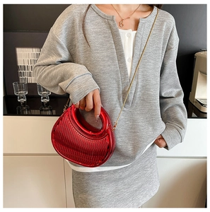 Detail of red metallic crescent bag with vertical textures and gold chain strap