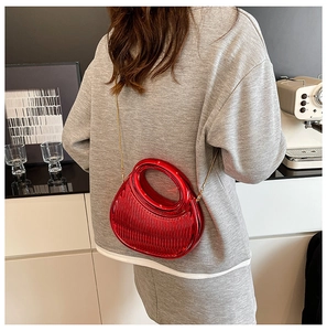 Close-up of bright red acrylic crescent bag with vertical stripes and gold chain strap