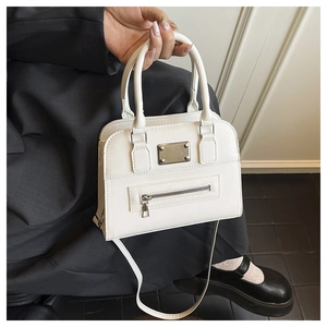 Close-up of a white Boston bag showing silver metal plaque and smooth leather texture