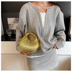 Detail of gold crescent evening bag with vertical texture and round metal handle
