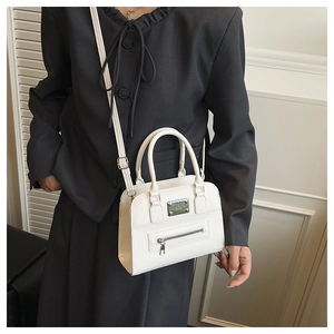 Detail of white Boston handbag with metal plate, front zipper pocket and round handles