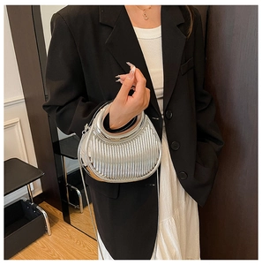Detailed close-up of silver crescent handbag with pleated texture and metal handle
