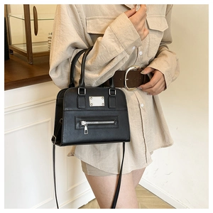 Close-up of a matte black leather handbag with silver zipper and metallic plate detail