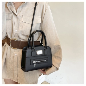 Classic black leather Boston bag with metal zipper detail shown in casual street style