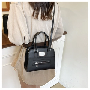Detail of a chic black leather tote bag with silver hardware on a person