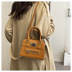 Detail of ginger yellow leather tote with dual handles and front metal decoration