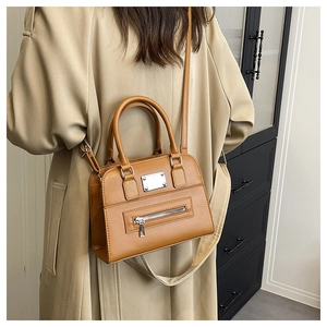 Detail view of the brown leather Boston bag with functional zippers and smooth handle