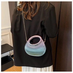 Metallic iridescent pleated crescent bag with gold chain strap worn on black suit