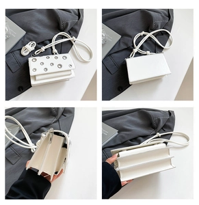 Detail view of white leather crossbody bag with metal eyelets and accordion compartments