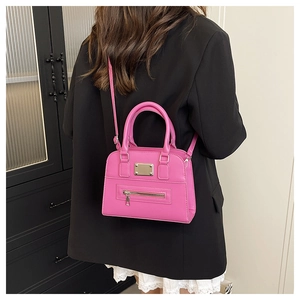 Pink PU leather shoulder bag shown on model with metal plate and zip pocket detail