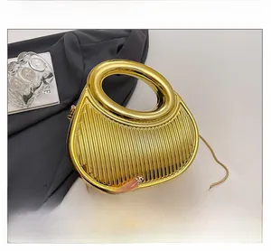 Detailed shot of golden crescent clutch with vertical texture and metal ring handle