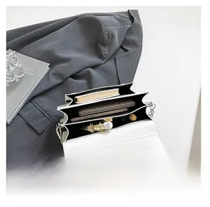 Three-compartment white leather handbag interior showing storage for phone and cosmetics