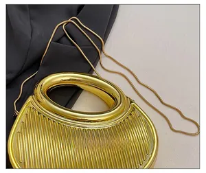 Detail shot of the vertical ribbed gold texture and elegant snake chain on the evening bag