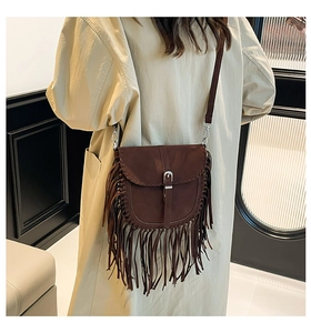 Macro detail of dark brown vintage fringe crossbody bag with suede texture and metal buckle