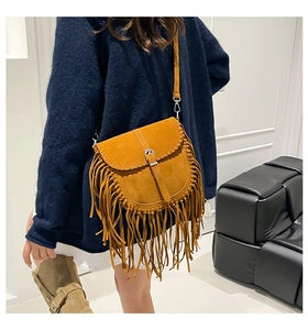 Detail of bohemian saddle bag featuring long suede tassels and braided leather edges