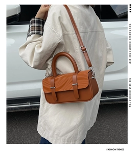 Brown box-shaped shoulder bag with wave texture and dual straps in an outdoor setting