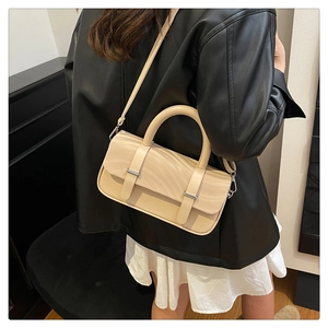 Detail view of cream crossbody bag featuring wavy texture and silver metal buckles