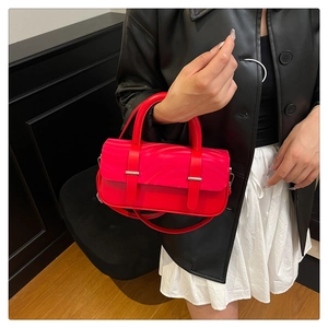 Detail of red leather crossbody box bag with silver hardware and top handle strap
