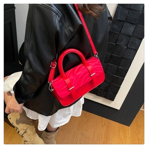Detail of red ripple textured box bag worn by model with black leather jacket and white dress