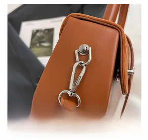 Macro shot of silver polished hardware and stitching on brown leather box handbag