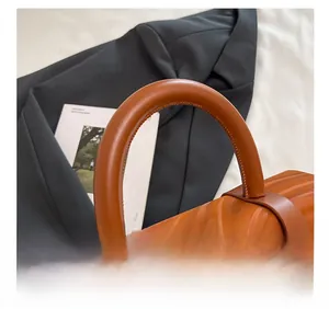 Detail of the caramel leather handle and silver metal buckle on a small box bag