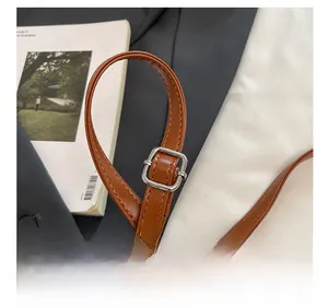 Detail of adjustable caramel leather shoulder strap with a polished silver buckle